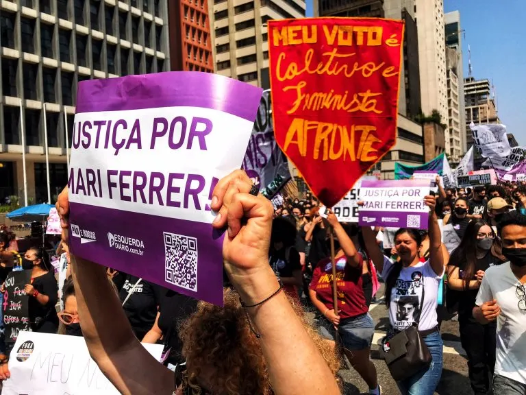 Manifestantes seguram cartazes em um protesto de rua. Os cartazes dizem: JUSTIÇA POR MARI FERRER!