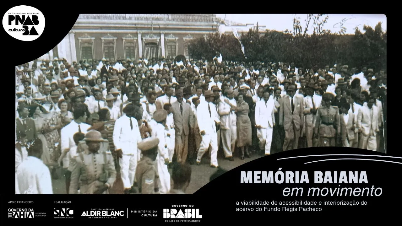 Fotografia em preto e branco de 1951. No canto esquerdo superior da imagem está a Prefeitura de Vitória da Conquista e o lado direito possui árvores. Régis Pacheco traja um terno branco, posicionado próximo ao centro da imagem e olha para o canto direito da foto. A imagem aparenta ter centenas de pessoas. Uma mulher de vestido longo está abraçada a Régis Pacheco. Militares fardados estão na ponta inferior esquerda e direita da foto, localizados próximos ao político, e criam um espaço mais vazio na parte direita inferior da fotografia. Instrumentos de sopro estão na multidão.Entre os trajes dos civis é possível identificar homens usando ternos, gravatas e chapéus, e mulheres que trajam vestidos lisos e estampados. Contornando toda a fotografia está posicionada uma margem preta com as informações: “Memória baiana em movimento, a viabilidade de acessibilidade e interiorização do acervo do Fundo Régis Pacheco”, em letra cinza, e as logos do Governo da Bahia, Sistema Nacional de Cultura, Política Nacional Aldir Blanc, Ministério da Cultura e Governo Federal.